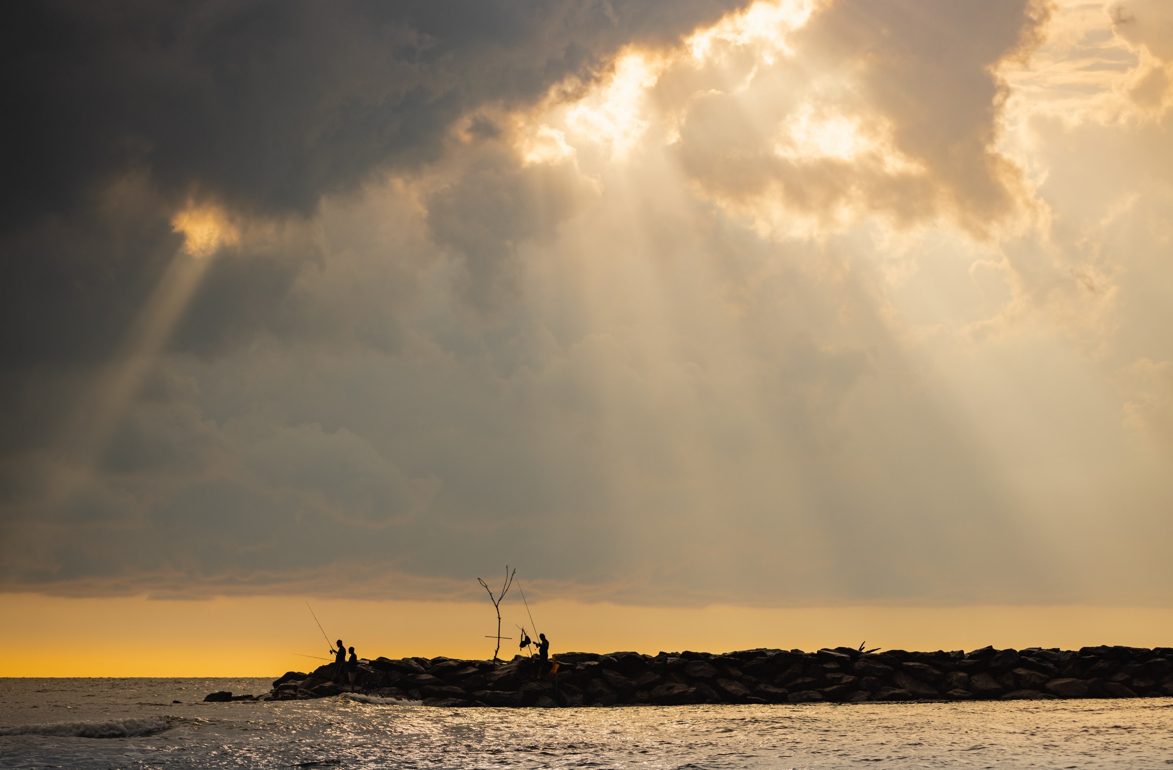 God-rays breken door de wolken boven zee, silhouetten op een golfbreker, Sri Lanka