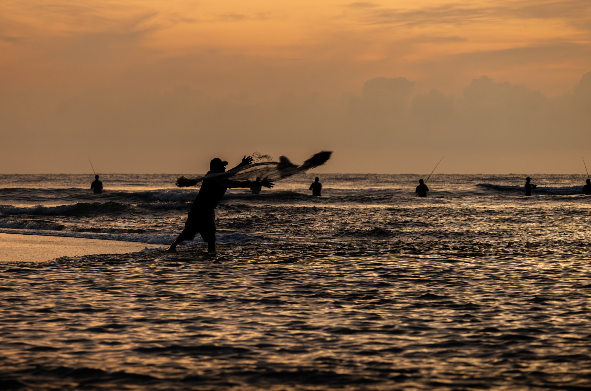 Vissers als silhouet op een golfbreker in het laatste goudlicht, Weligama, Sri Lanka
