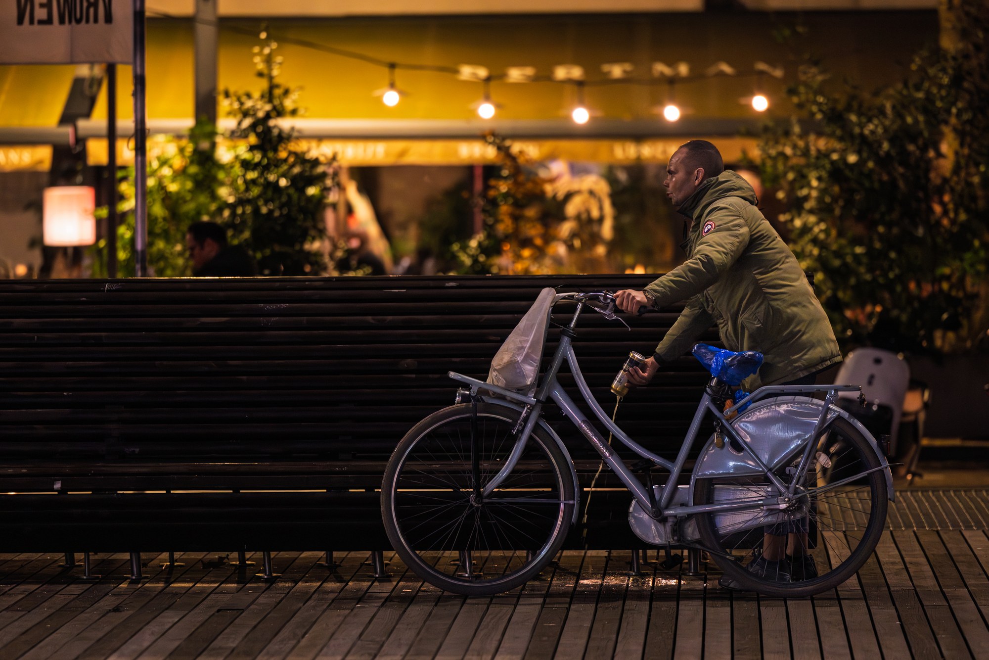 Fietser als silhouet langs een warm-verlichte gevel in de nacht, Nederland
